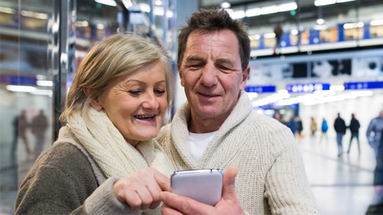 Pärchen am Bahnhof, dass gemeinsam auf das Handy schaut