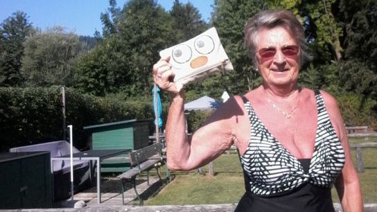 Frau im Garten mit Bikini und Täschchen in der Hand