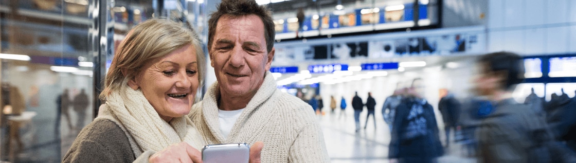 Pärchen am Bahnhof, dass gemeinsam auf das Handy schaut