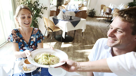 Frau der gerade ein Teller mit Essen gereicht wird